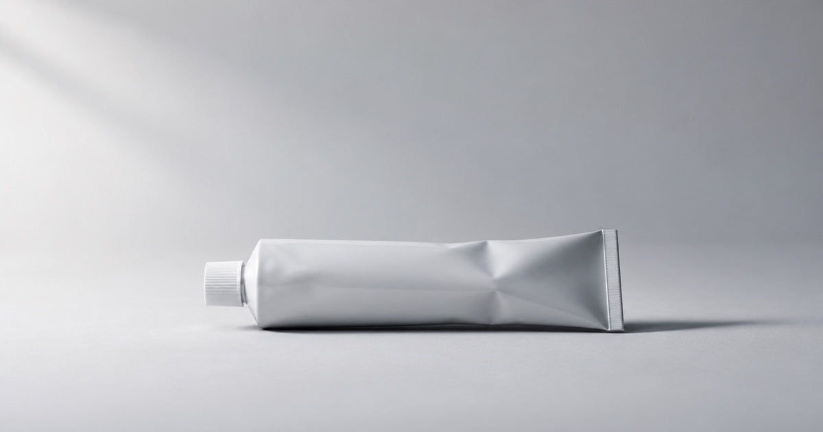 A single unbranded collapsible toothpaste tube resting on a plain surface.