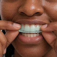 Placing a Mouth OS Mint Frost dissolvable toothpaste film on the front of the teeth before brushing