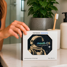 Clean Saint Mouth OS toothpaste film box on a modern bathroom vanity beside a toothbrush