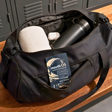 Mouth OS toothpaste film sachet tucked into a gym bag pocket with everyday essentials